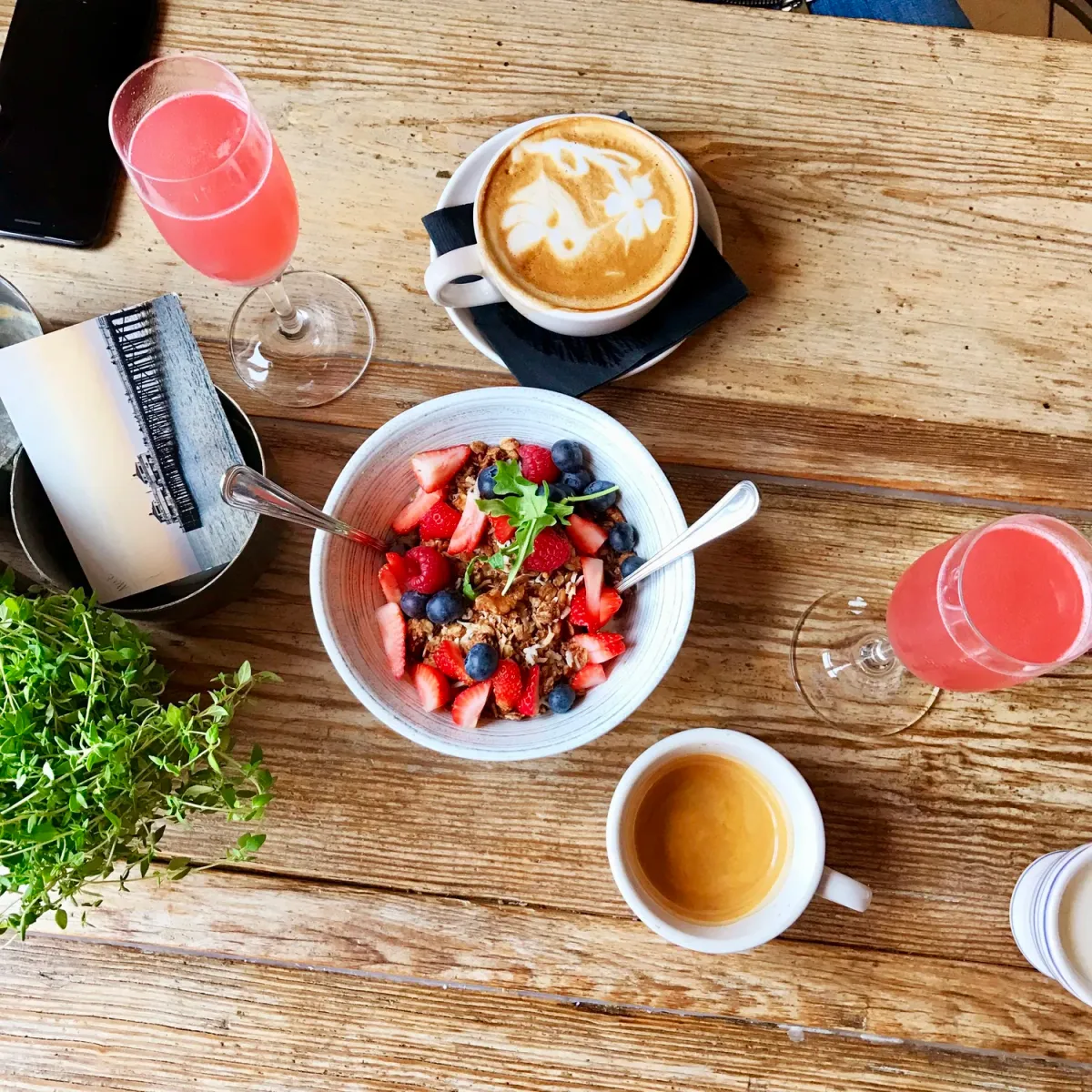 A Cookie Beacon brunch spread — a berry granola bowl, latte art, espresso and pink mimosas