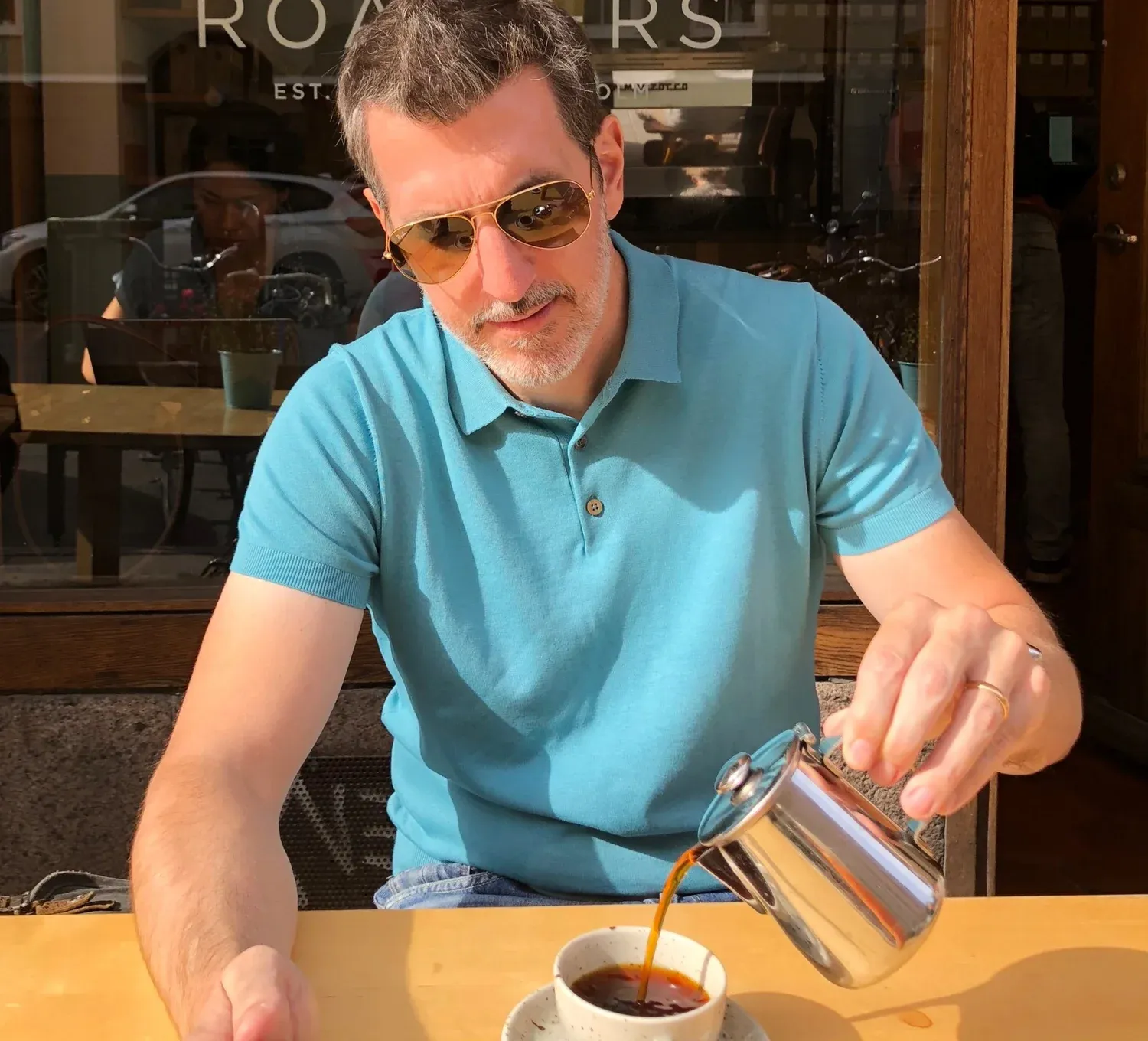 Pouring filter coffee at a sunny café table — a cafecito moment