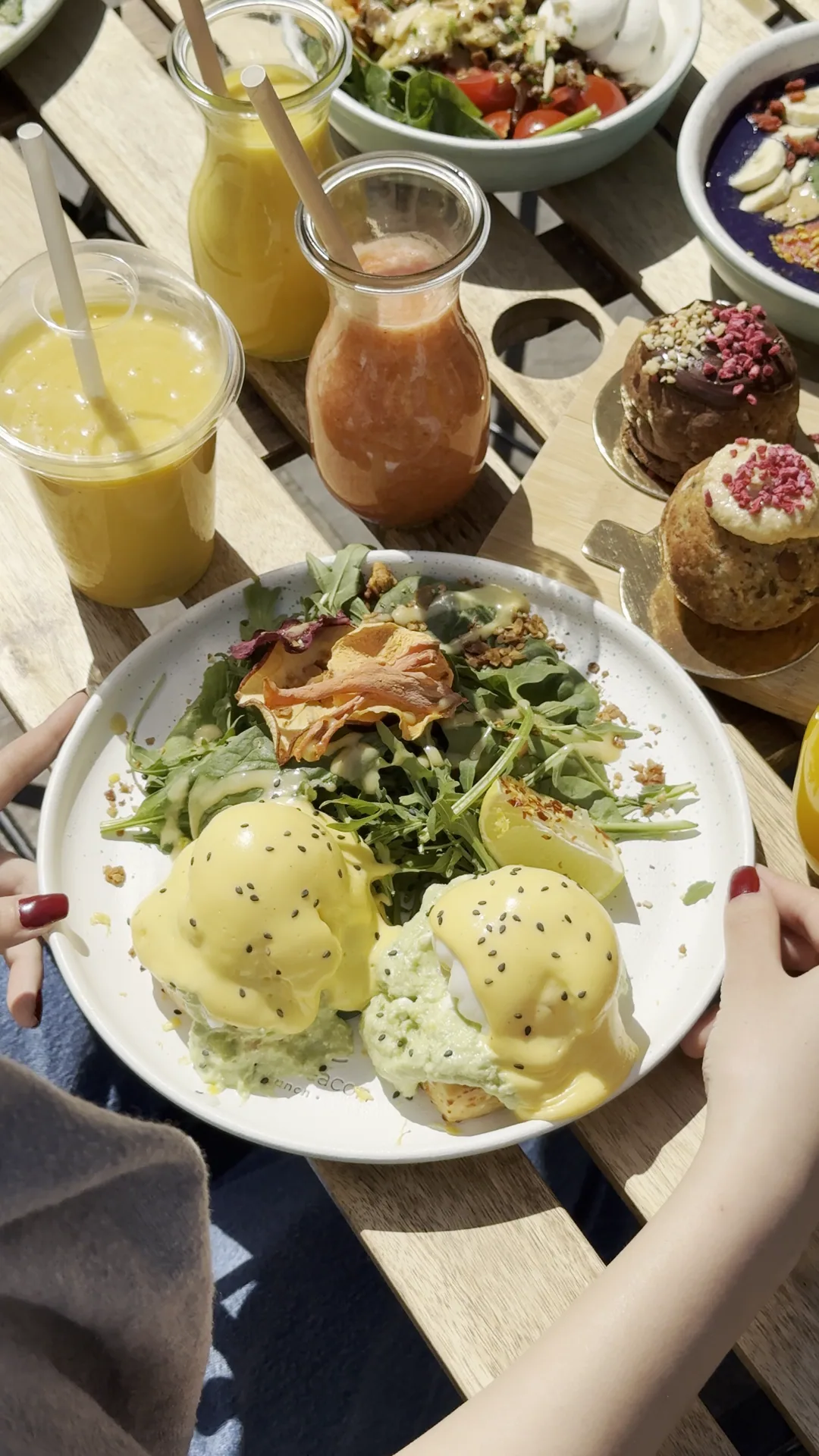 The Eggs Benedict on cheddar scones on a table at Cookie Beacon Basilica, with juices and chunky cookies around the plate