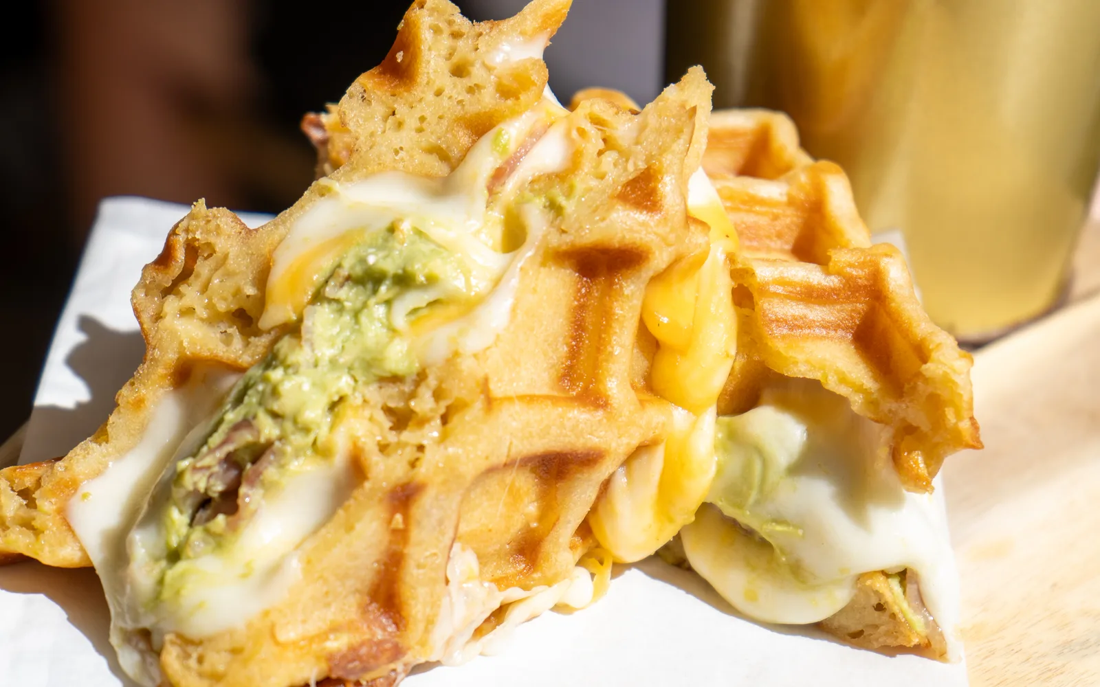 Grilled-Cheese Waffle-Sandwich közelről: olvadt sajt és avokádó a ropogós gofri között, a Cookie Beacon étlapjáról