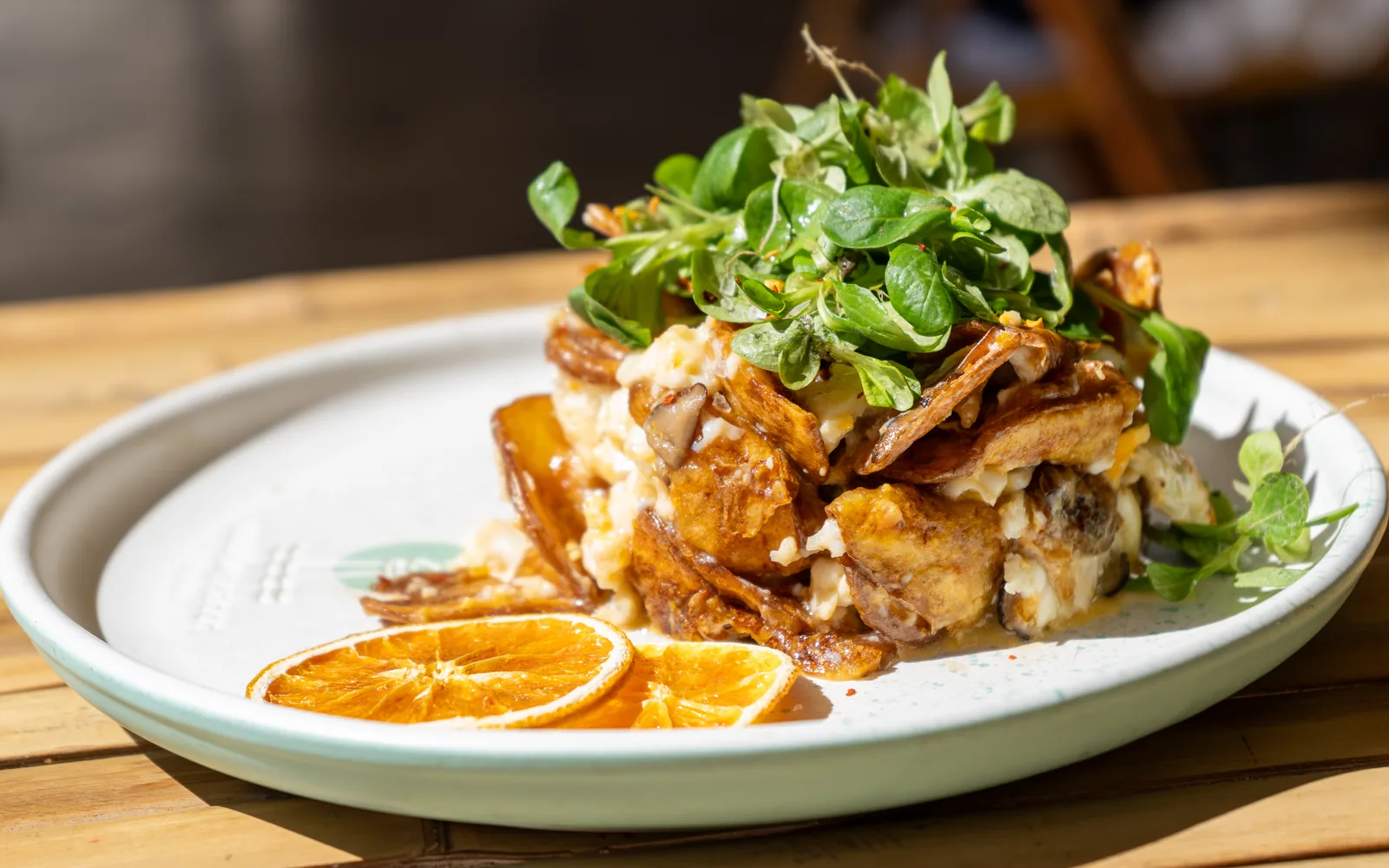 Madrid Smashed Eggs at Cookie Beacon Budapest — crispy potato shards and runny-yolk egg with sautéed shiitake, under a pile of leafy greens