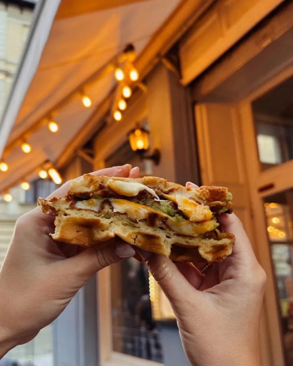 Grilled-cheese waffle sandwich held up outside a Cookie Beacon brunch spot