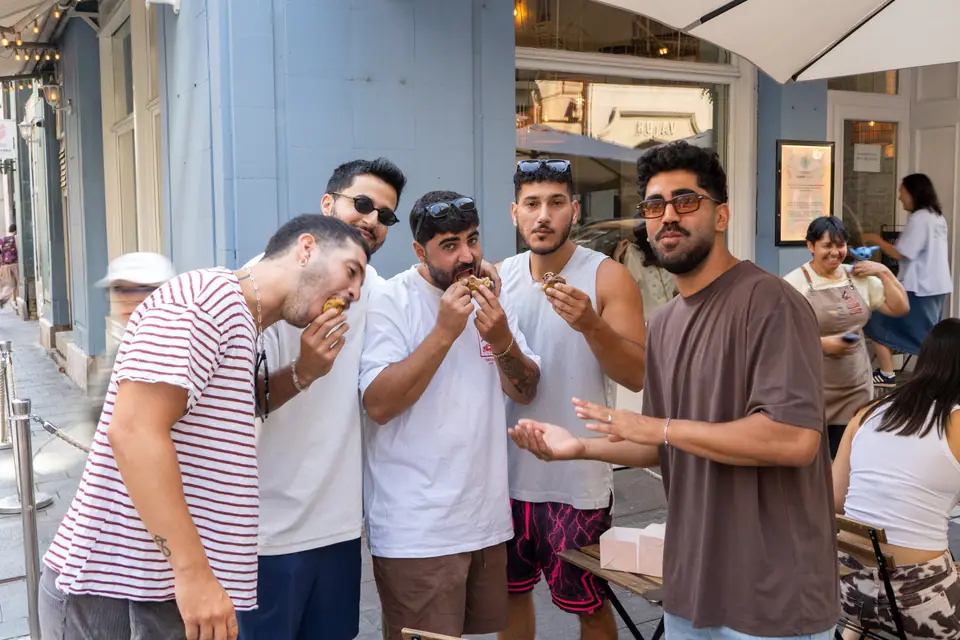 A group of friends standing outside Cookie Beacon Budapest eating chunky cookies straight from the box