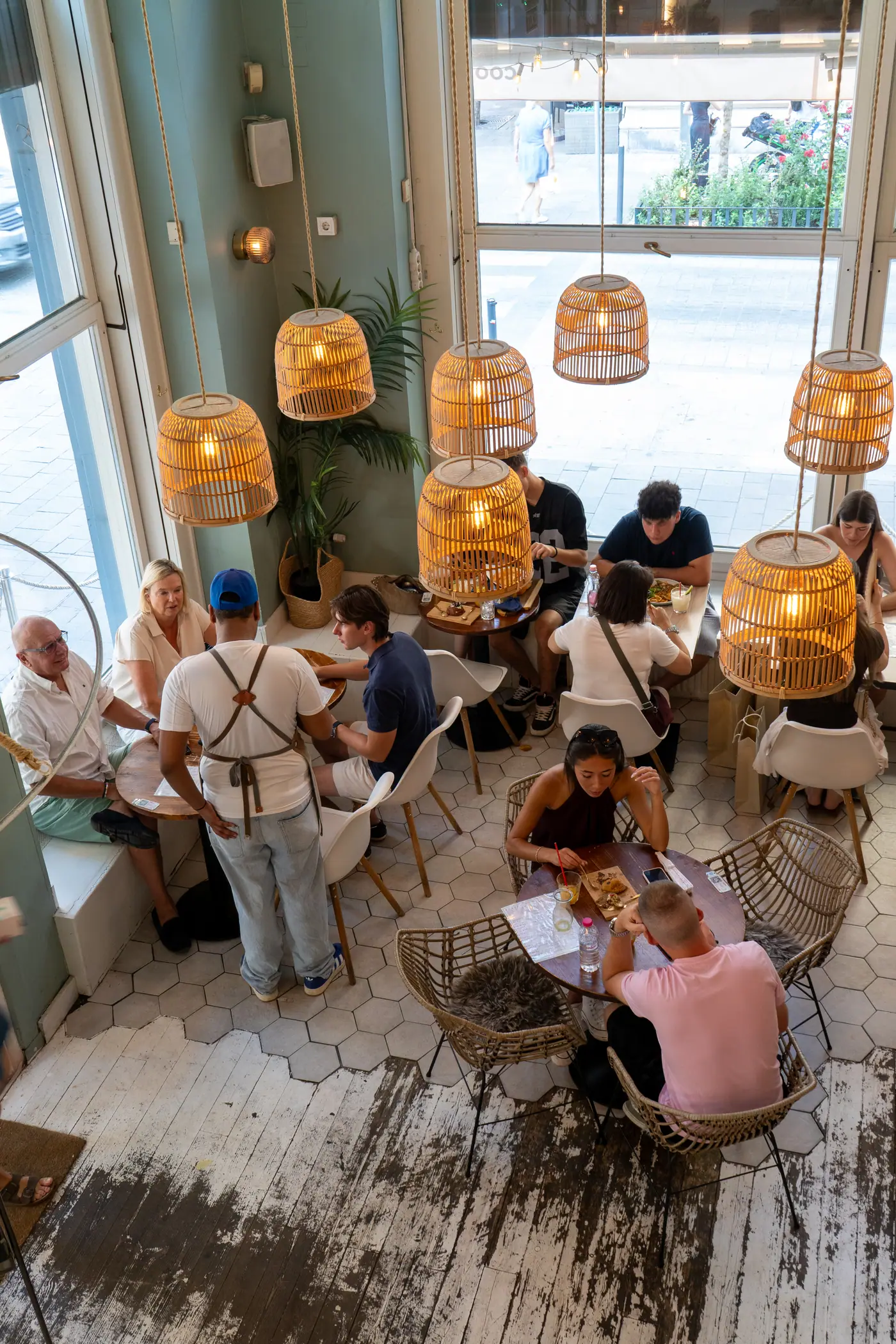 Rattan lamps glowing over busy brunch tables at Cookie Beacon Basilica