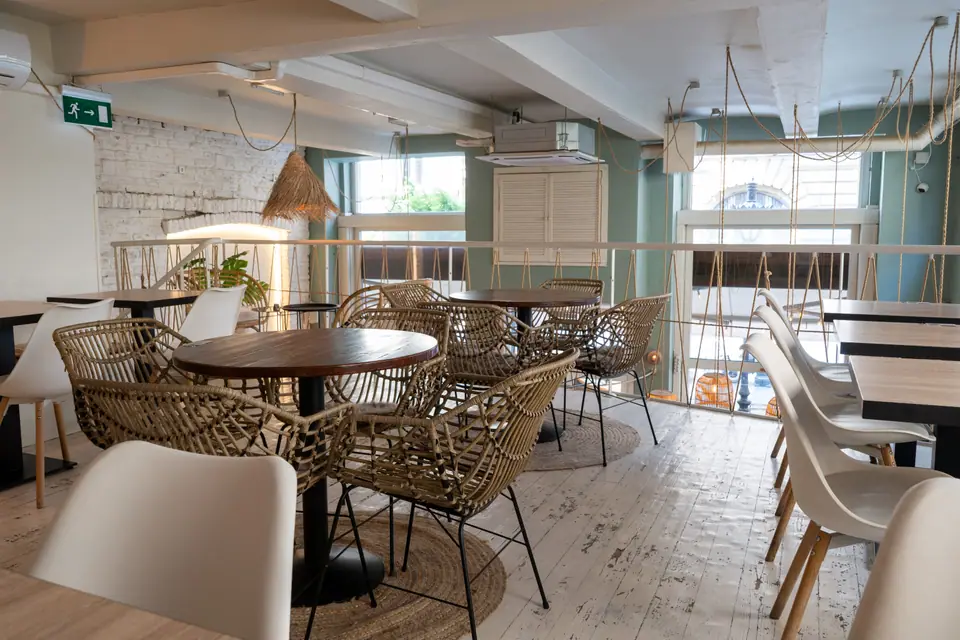 The upstairs room at Cookie Beacon Budapest with rattan chairs, wooden tables and whitewashed floorboards
