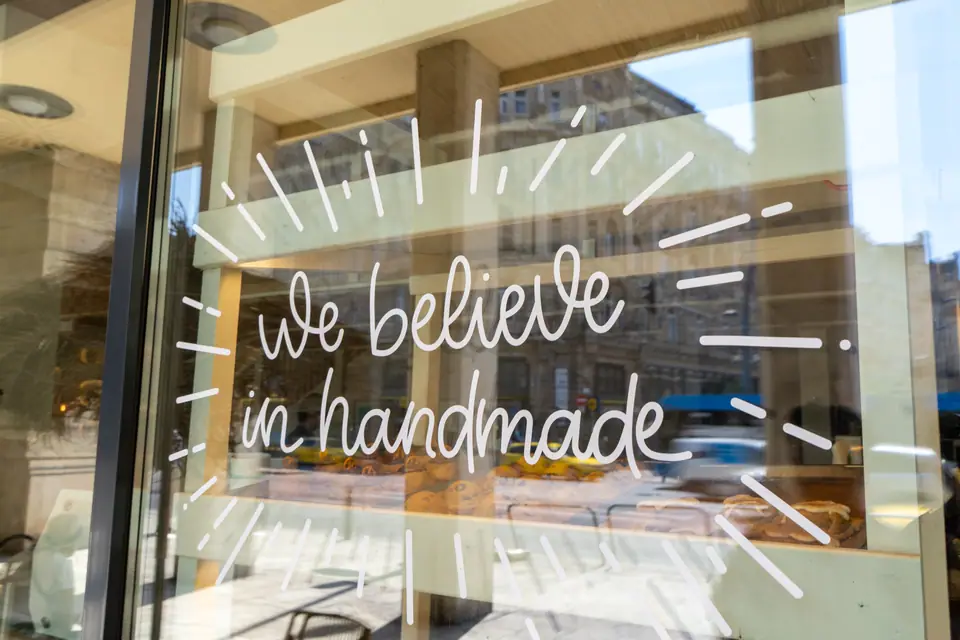 Belváros townhouses reflected in the hand-lettered window of Cookie Beacon on Ferenciek tere