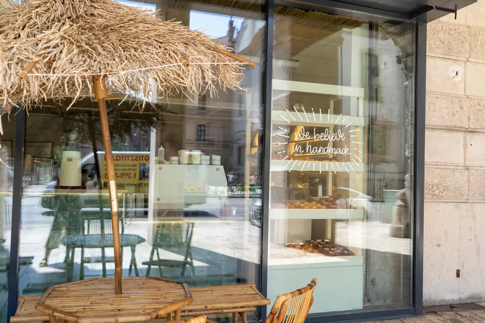 A straw parasol shading bamboo terrace tables outside Cookie Beacon on Ferenciek tere, Budapest