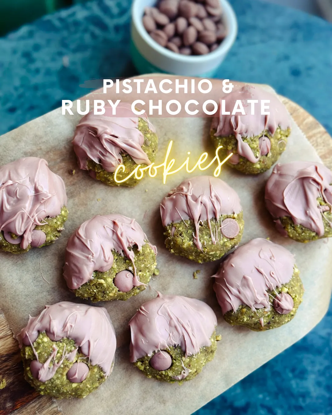 Green pistachio no-bake cookies half-dipped in pink ruby chocolate on a wooden board